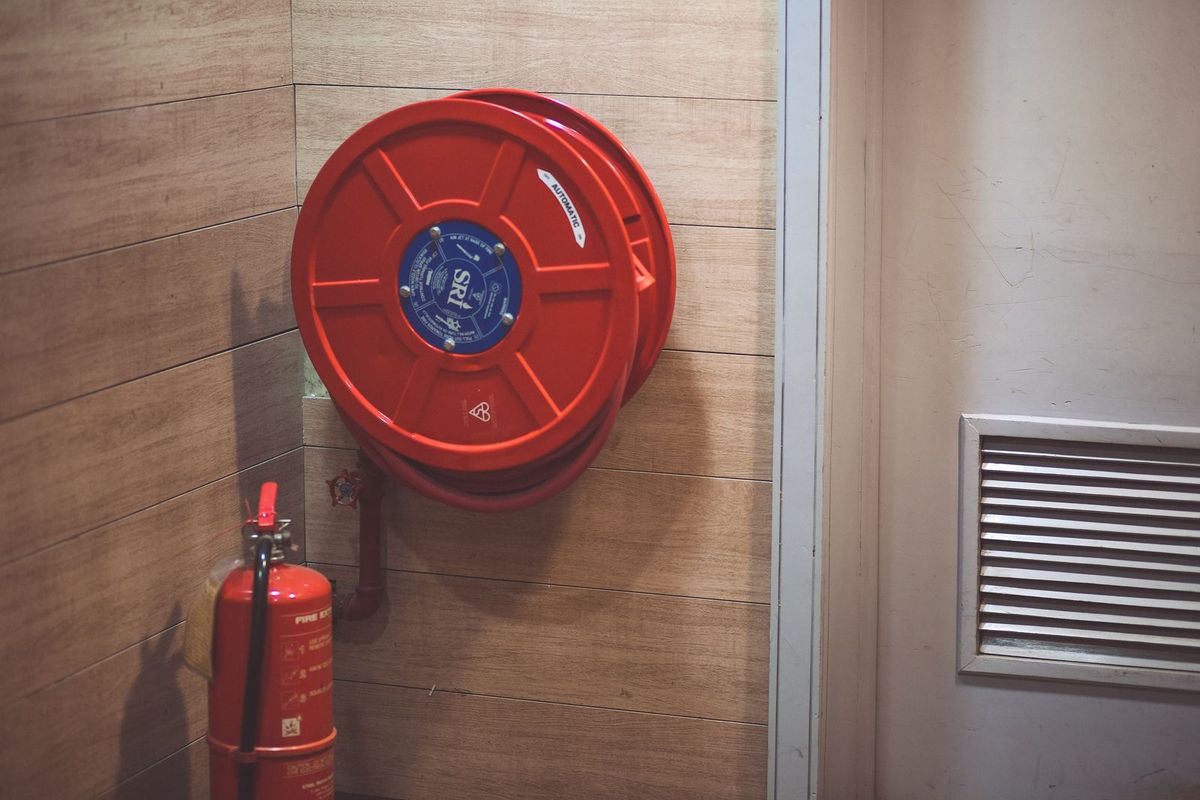 Hydrant wewnętrzny z wężem na zwijadle i gaśnica proszkowa przy ścianie
